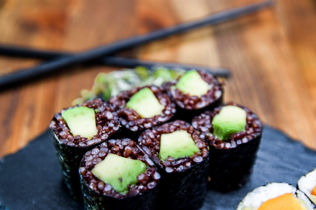 6 Avocado Ledight Maki Sushi Rollen auf einer schwarzen Schieferplatte